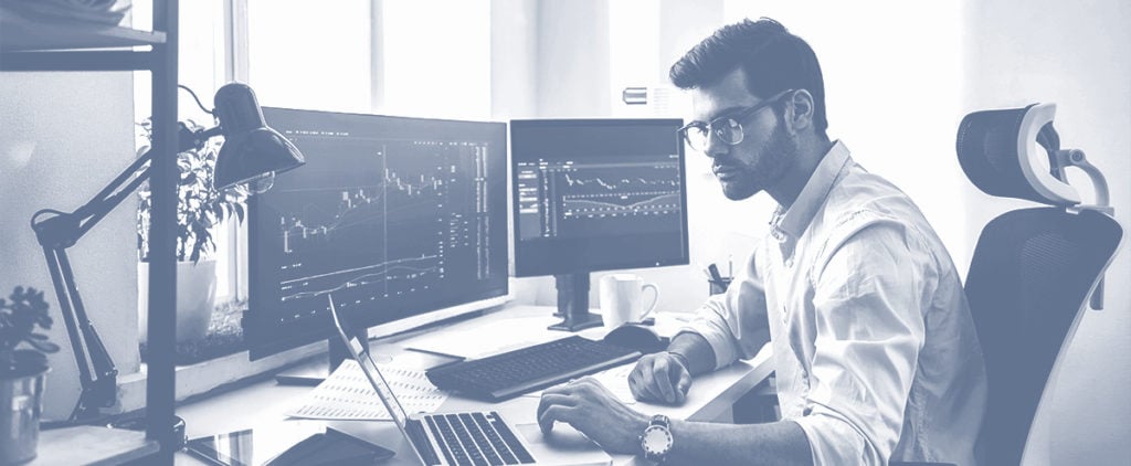 A man day trading in front of two computer screens